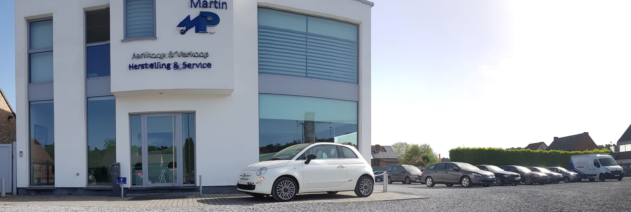 Witte Fiat 500 voor de ingang van Auto's Martin in Heusden-Zolder